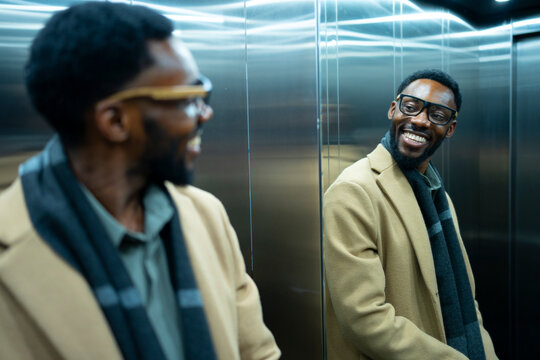 Smiling man in elevator reflecting confidence and style