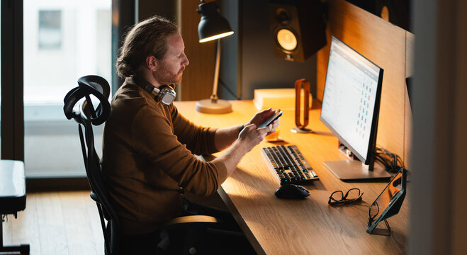 Man working at desk in home office at evening
