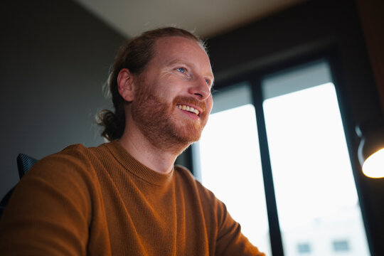 Smiling man enjoys his work at home during evening hours
