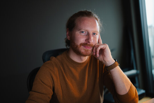 Man with ginger beard in casual sweater sitting thoughtfully
