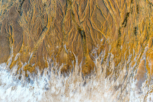 Golden salt-flat channels branching across cracked earth