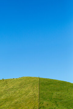 Hill paddock divided by fence on farm.