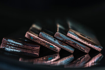 Oxidized coated copper busbars, non-ferrous metal products for the power industry, close-up view with industrial lighting