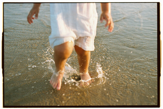 Feet of child splashing in shallow ocean water