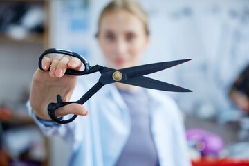 Artistic young woman demonstrating mastery with large tailoring scissors in creative studio setting