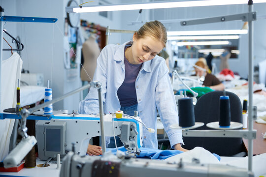 Young seamstress inspecting and ensuring quality of industrial sewing work