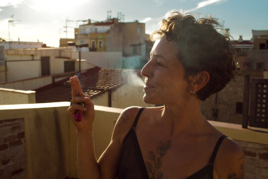A young woman is smoking on her terrace.