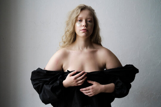 Model posing in black clothing against a plain backdrop