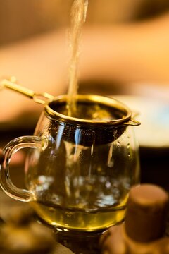 Hot Tea Being Poured Into a Glass Cup With a Strainer