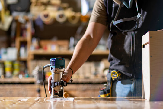Carpenter grap a Wood Router on Workbench in Bright Workshop