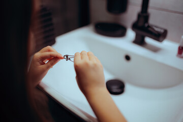 Child Cuts His Own Nails With Nail Clippers At Home In The Sink. Self reliant kid taking care of her fingernails