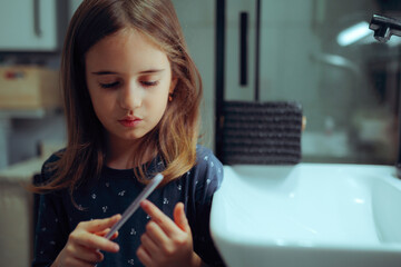 Little Girl Files Her Nails with a Nail File at Home. Self reliant kid taking care of her fingernails
