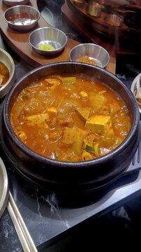 Boiling Korean Traditional Kimchi Stew with Tofu in an Earthen Pot (Ttukbaegi)
