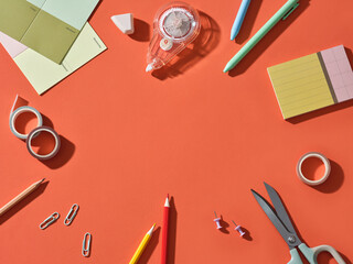 Colorful stationery and office supplies arranged on a vibrant orange