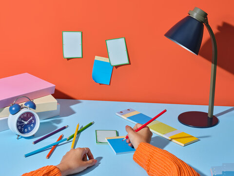 Creative workspace with colorful pencils, notepad, and alarm clock
