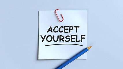 Accept yourself message on a paper held by a red clip and blue pencil