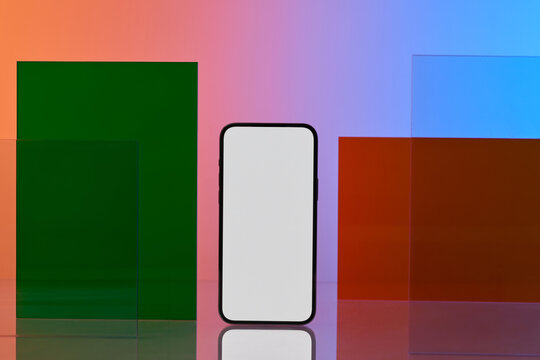 A sleek smartphone stands in front of colorful geometric shapes