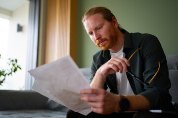 Man reading documents while sitting on a couch in a room
