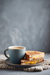 grilled cheese sandwich served alongside a steaming cup of coffee, creating a warm and cozy food scene. This simple comfort meal concept evokes relaxation, casual dining, and everyday indulgence, maki