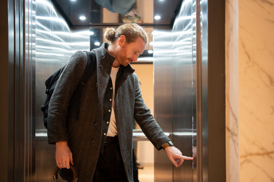 Man presses button in elevator during busy day at office
