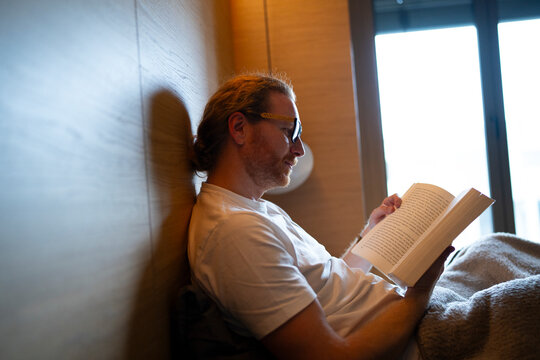 Man reading a book in a cozy bedroom on a quiet morning