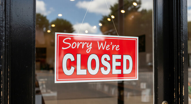 Sorry we're closed sign hanging on a glass door, indicating business closure
