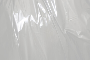 plastic transparent cellophane bag on white background. The texture looks blank and shiny. The plastic surface is wrinkly and tattered making abstract pattern