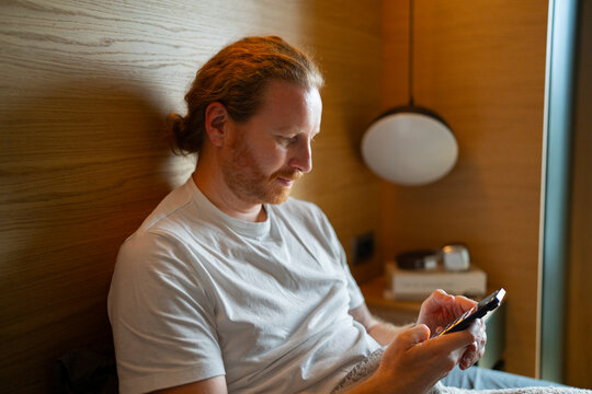 Man uses smartphone while sitting indoors in a modern setting
