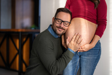 Man in love hugs his pregnant wife, they are waiting together for the baby's arrival. Love, family