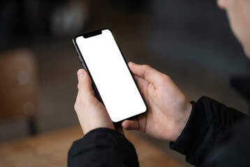 Man in a black coat holding a modern smartphone with a blank white screen to showcase a new mobile application interface, browse digital content, and demonstrate user experience (UX) design in a casua