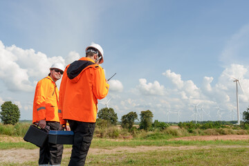 Engineer workers walking toward wind turbine carrying maintenance equipment preparing outdoor renewable energy task promoting sustainable electric generation teamwork innovation green technology