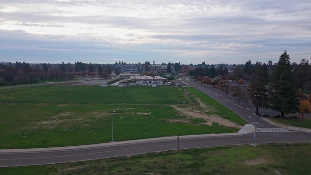 Descending drone view of Cal State Stanislaus close to sunset. Jib shot, cloudy, late afternoon, 4K.