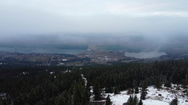 Canadian Winter Landscape over Forest Trees above valley lakes in Lake Country British Columbia. Low fog and clouds on gloomy winter day.
