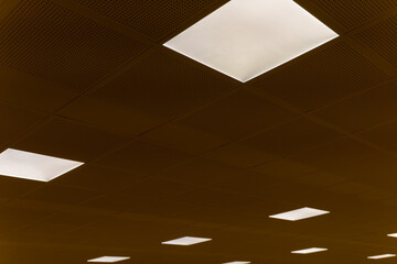 Light panels illuminate a modern office ceiling creating a streamlined and vibrant workspace