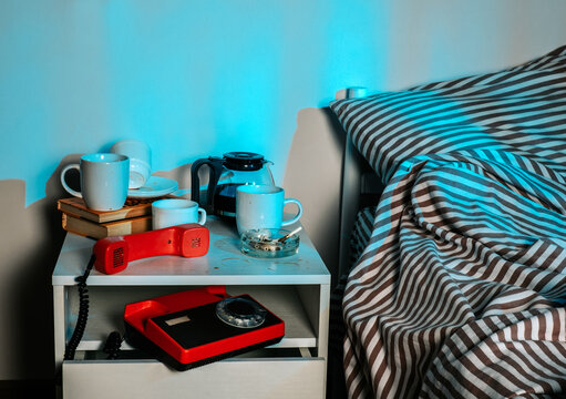 Messy bedside table with coffee and objects at night symbolizing insomnia
