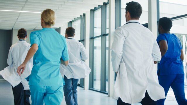 Medical team running through clinic hallway toward emergency operation room. Focused professionals moving quickly showing urgency and coordination. Healthcare staff responding fast.