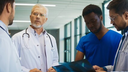 Doctors gathered around difficult X-ray. Team debating patient condition in bright hallway. Colleagues struggling agreeing on diagnosis while reviewing chest scan. Everyone talking.