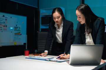 Financial analysts work overtime analyzing data on tablets, laptops, and graphs. Collaboration, teamwork, and planning.