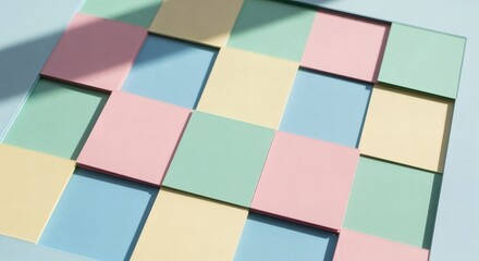 Layered paper checkerboard is arranged into a playful abstract composition with pastel tones. Modern craft concept
