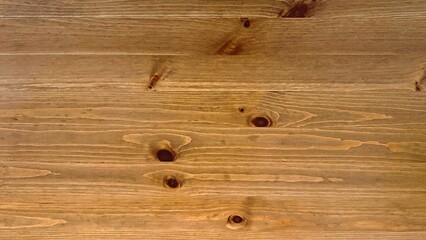 Knotted wooden tabletop with warm grain and visible knots, closeup of pine plank surface showing natural finish and subtle imperfections, ideal for food photography, furniture styling, workshop