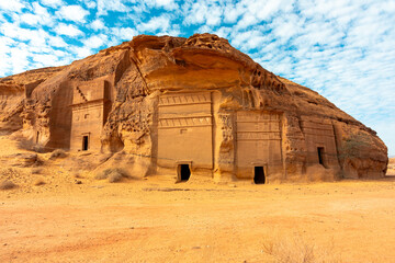 Hegra, Saudi Arabia - ancient desert cliff tomb with carved facades beneath a bright sky