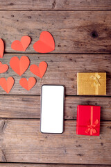 Directly above shot of smart phone by gifts and heart shaped decoration on table, copy space