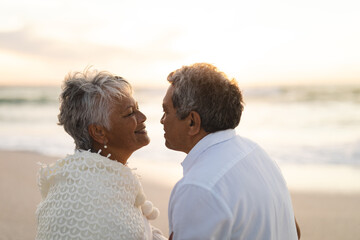 Naklejka premium Side view of happy multiracial senior couple looking at each other romantically during sunset