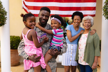Portrait of smiling african american family with military soldier standing at house entrance