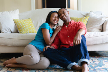 Obraz premium Full length portrait of smiling young african american couple sitting together in living room