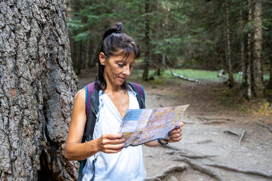 Woman reading map during forest hike for navigation outdoors