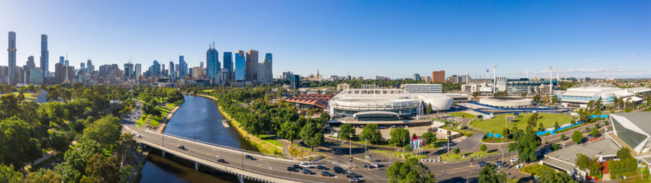 Aerial panorama of a bridge over a river alongside sporting stadiums and a city skyline