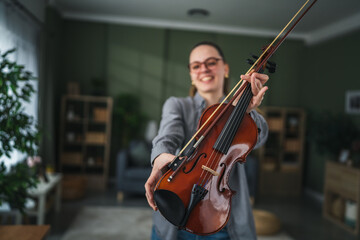 Woman holding up violin instrument and bow smiling