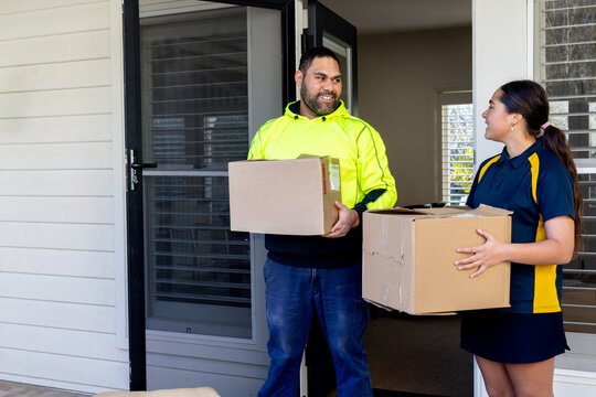 Man and girl (father and daughter) carrying moving boxes at the front door of a house