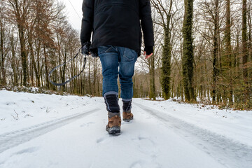 Person walking along snowy forest path carrying camera in winter